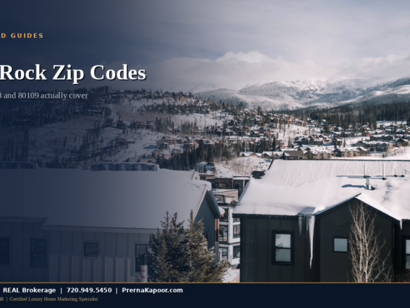 Snow-covered homes in a Colorado residential neighborhood with mountains in the distance